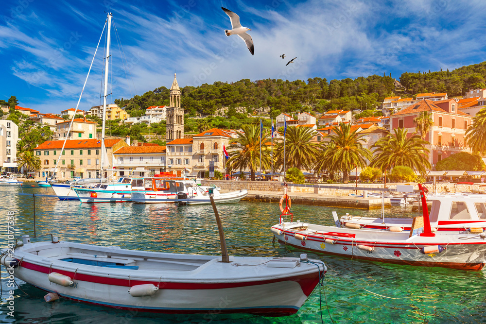 View at amazing archipelago with fishing boats in front of town Hvar, Croatia. Harbor of old Adriatic island town Hvar with seagull's flying over the city. Amazing Hvar city on Hvar island, Croatia.