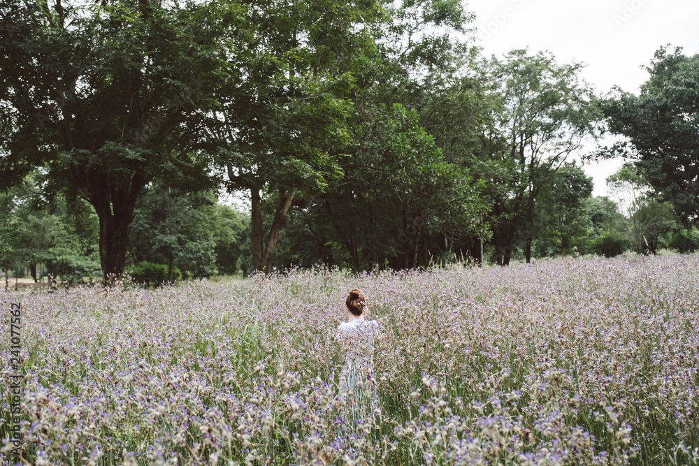 Woman with the white dress in the middle of the meadow with violet flowers Murdannia Giganteum in Prachinburi, Thailand. Photographer in nature. 