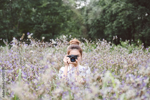 Woman with a camera the middle of the meadow with violet flowers Murdannia Giganteum in Prachinburi, Thailand. Photographer in nature. 