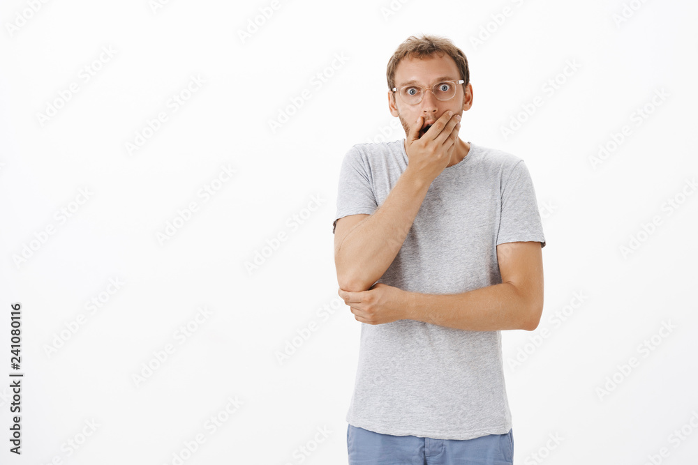 Portrait of shocked guy finding out terrible awful truth. Portrait of speechless concerned and shook unshaven male in glasses covering opened mouth with palm staring worried at camera Portrait of shocked guy finding out terrible awful truth. Portrait of speechless concerned and shook unshaven male in glasses covering opened mouth with palm staring worried at camera