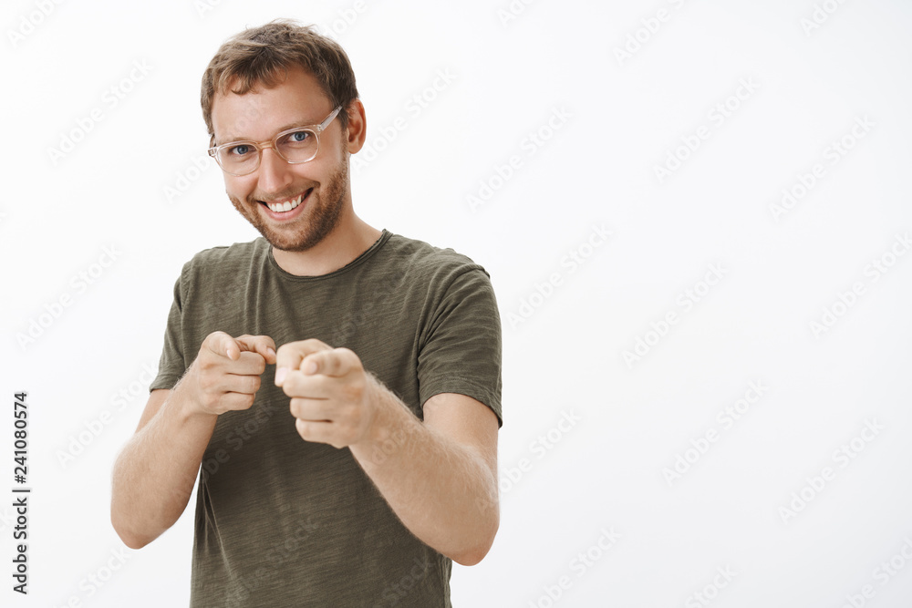 You are what we need. Enthusiastic happy and confident guy with bristle in glasses and dark-green t-shirt pointing with finger gun gesture at camera as if picking candidate with broad satisfied smile