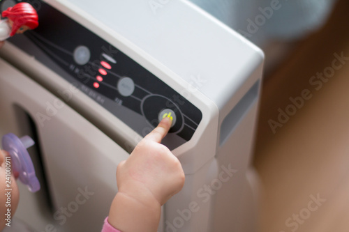 The baby's hand pressing the power button on the air purifier to clean up the polluted air.