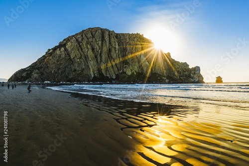 Rock on the beach during sunset, rays of the sun and colorful sky, Morro Rock photo