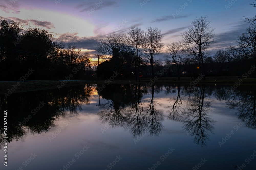 Mirror rejections on the placid surface of a pond at sunset in Tracy City, Tennessee