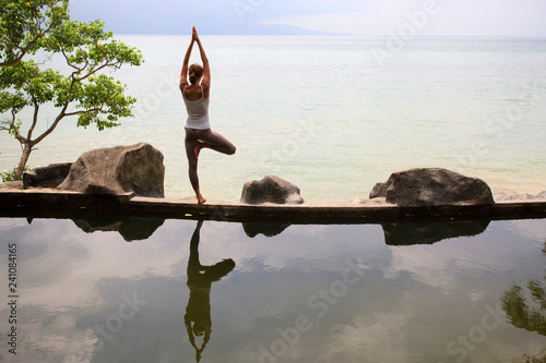 Woman practicing morning meditation Yoga at the beach
