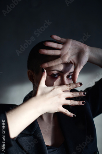 Girl with short haircut hides her face with hands
