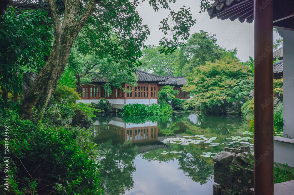 Traditional Chinese house by pond with reflection in water, in a Chinese garden, near West Lake, Hangzhou, China