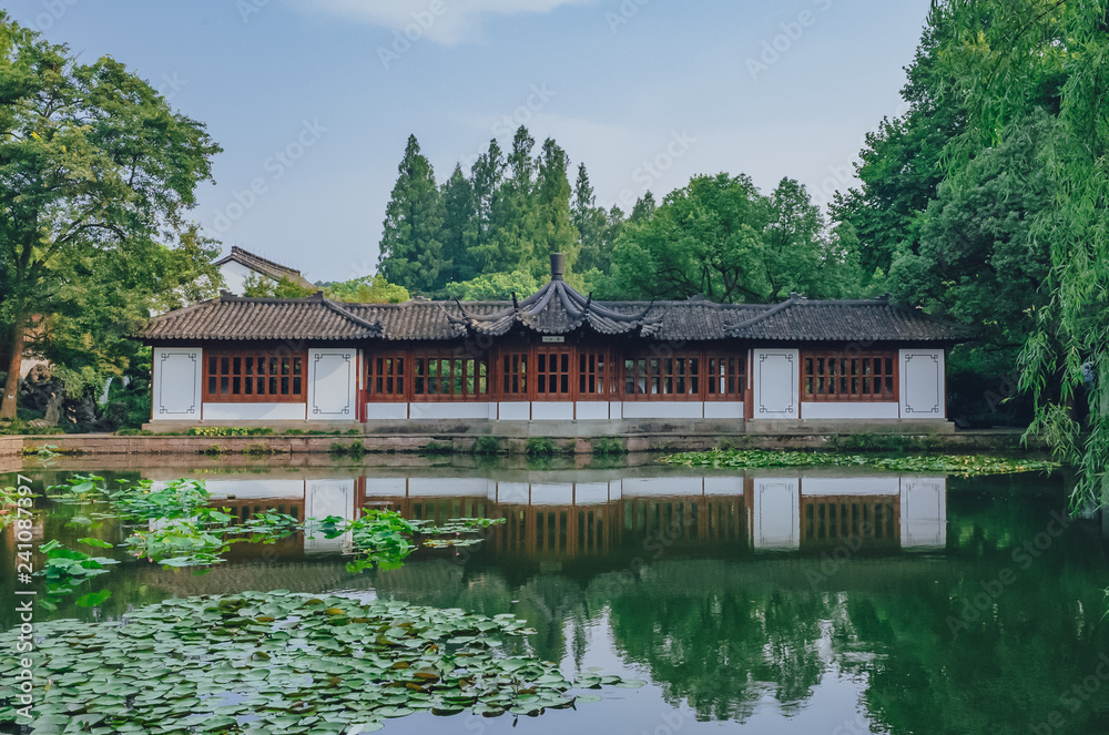 Traditional Chinese house by pond with reflection in water, in a Chinese garden, near West Lake, Hangzhou, China Traditional Chinese house by pond with reflection in water, in a Chinese garden, near West Lake, Hangzhou, China