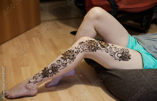 female leg with arabic or indian mehendi. Lotus flowers and beads. Beauty and fashion concept. traditional patterns or henna in Russian style