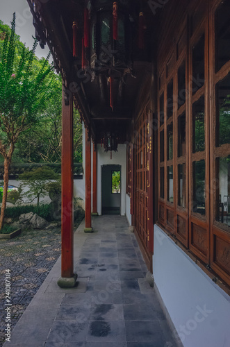 Covered path by house leading to a doorway in a Traditional Chinese garden, near West Lake, Hangzhou, China