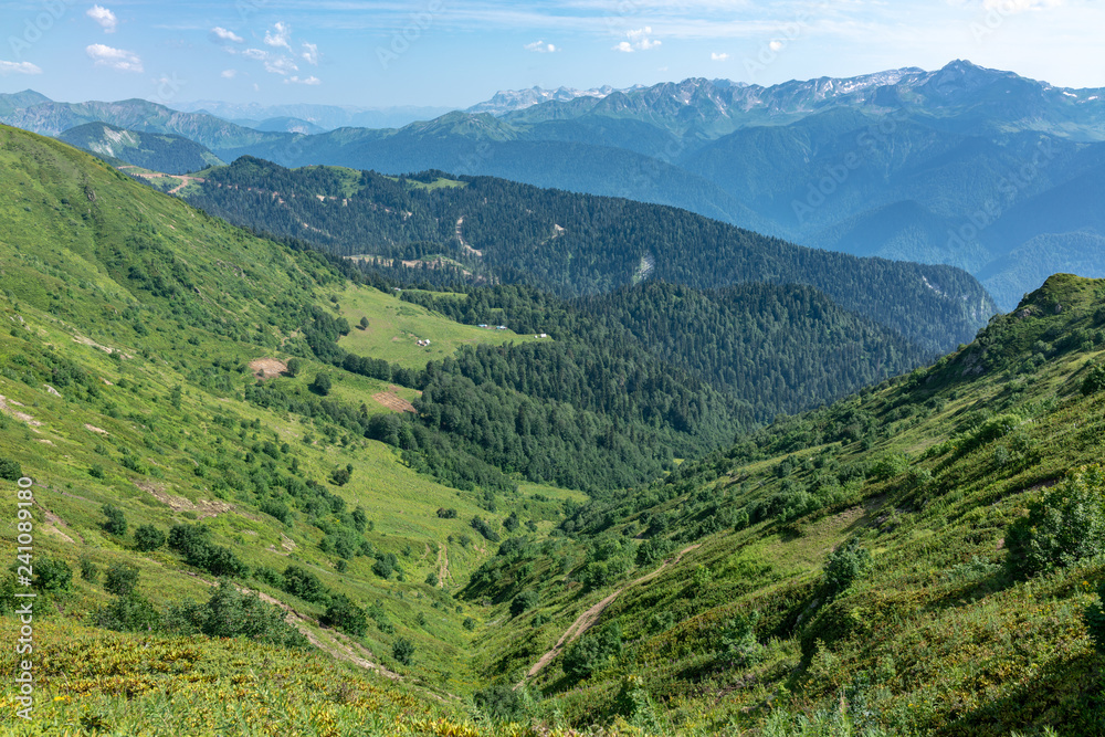 View over the Green Valley, surrounded by mountains vyskokimi on a clear summer day. Krasnaya Polyana, Sochi, Caucasus, Russia.