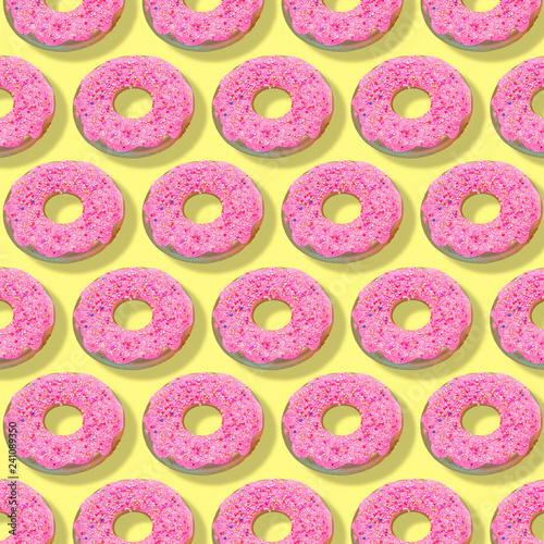 Creative art made with pink doughnuts pattern on yellow background..