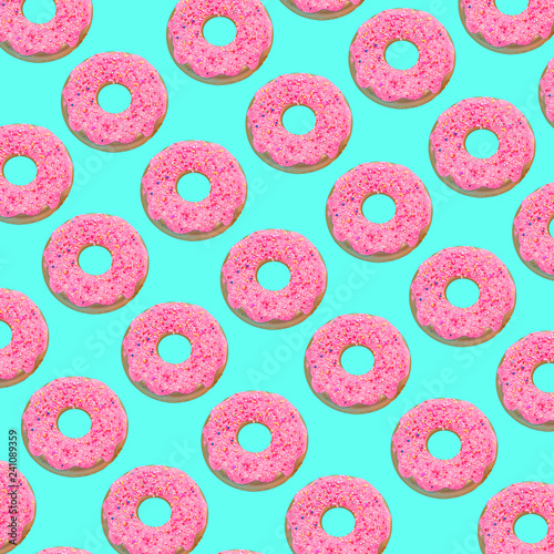 Creative art made with pink doughnuts pattern on turquoise background..