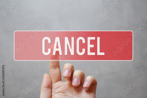 Cancel - hand pressing red transparent button on virtual touchscreen interface on grey background with copy space. 