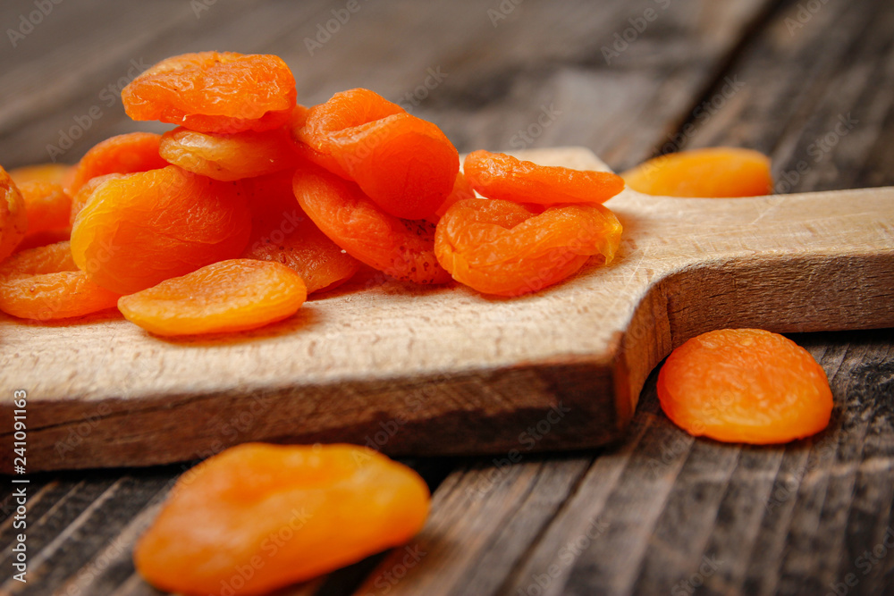 Dried apricots and kitchen cutting board on a old wooden table Dried apricots and kitchen cutting board on a old wooden table