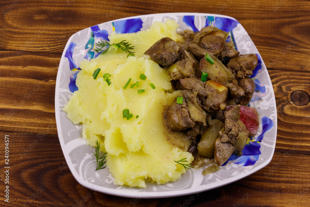 Mashed potatoes with stewed chicken liver with apple and onion on wooden table Mashed potatoes with stewed chicken liver with apple and onion on wooden table