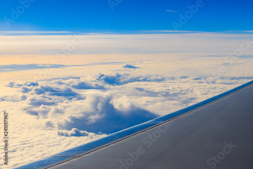 Wing of airplane flying above the clouds in the blue sky © olyasolodenko