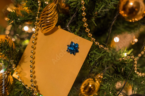 Wallpaper Mural horizontal image with close-up detail of a Christmas card with a small blue cockade, hanging on a Christmas tree with gold-colored decorations Torontodigital.ca