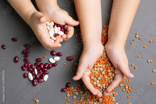 kids hands holding red and white beans, green and orange lentils