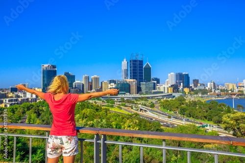 Carefree woman overlooking Perth Water, a section of Swan River, and central business district of Perth from Kings Park, the most popular visitor destination in Western Australia. Blue sky, copy space