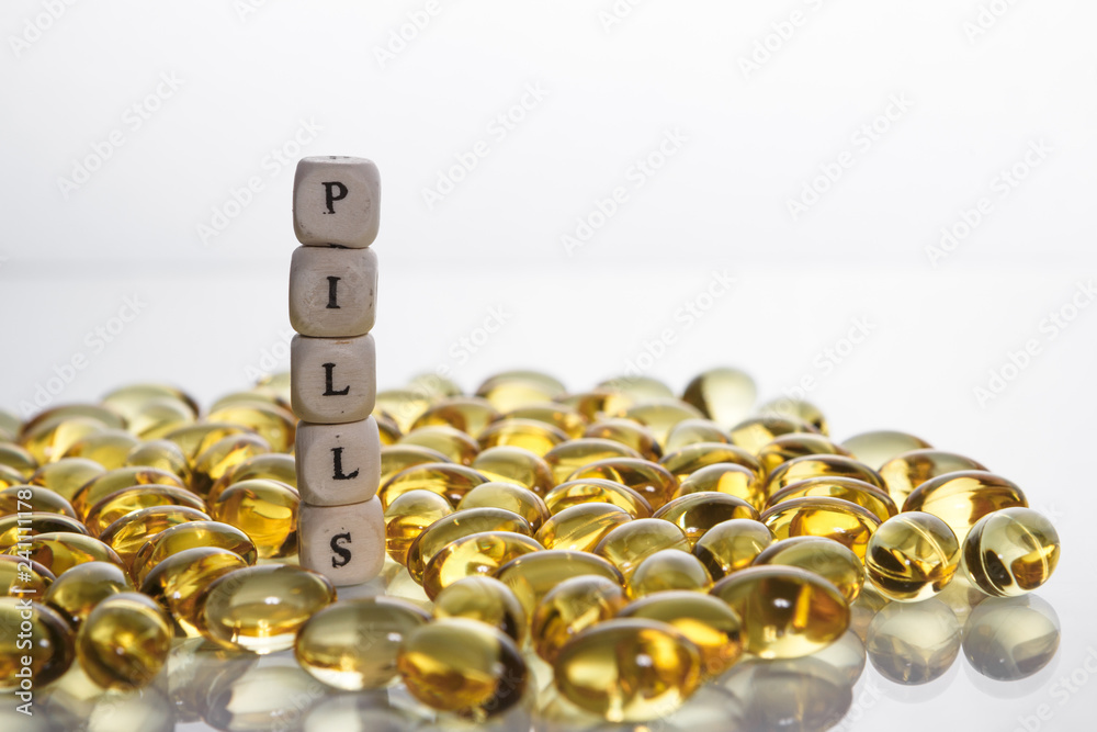 Word pills from the letters of cubes and Lecithin gel pills on light background.
