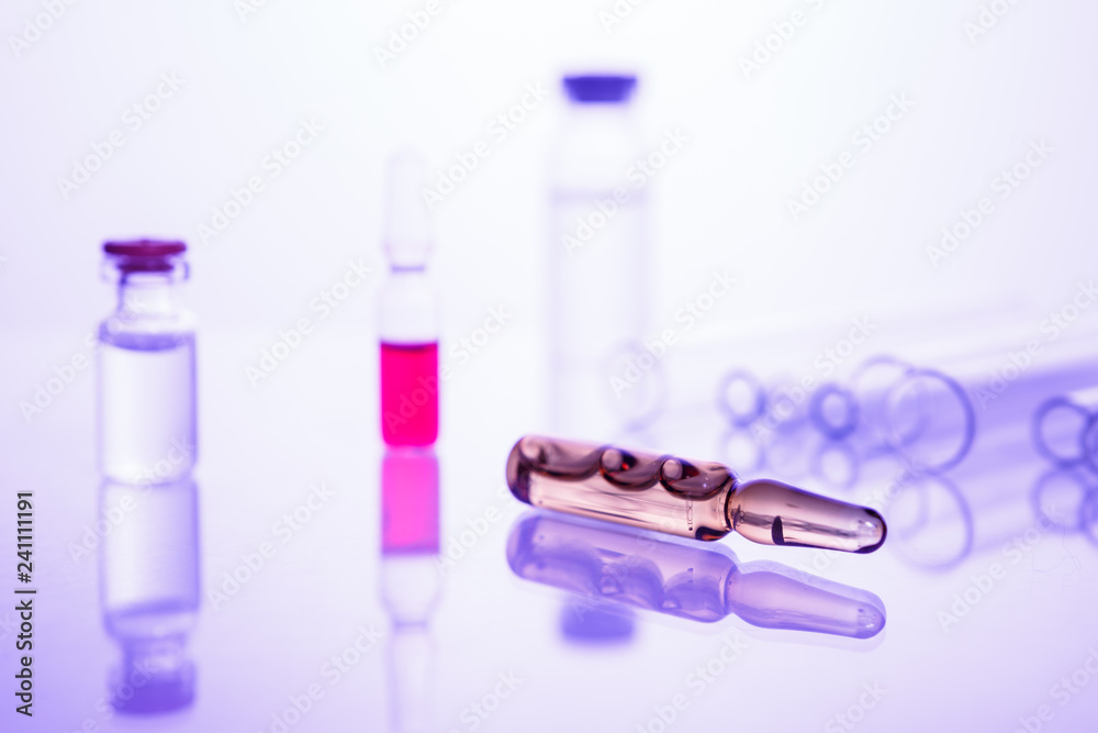 Group of vials with medication on blue methacrylate table.