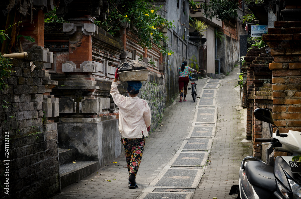 Balinese Asian woman carrying rocks on head
