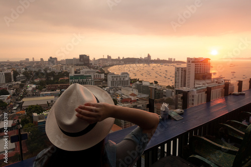 Tourist is watching beautiful sunset on the rooftop of hotel for Pattaya bay beach at dusk.