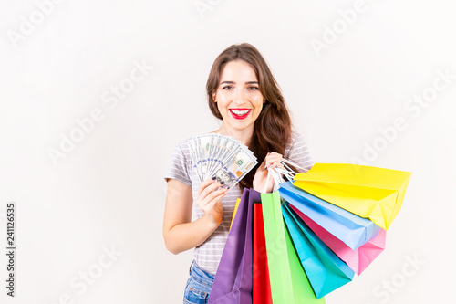 Spring summer season sale concept. Attractive young woman with long brunette hair, wearing slim fit casual shirt, holding many different blank shopping bags over white background. Copy space, close up