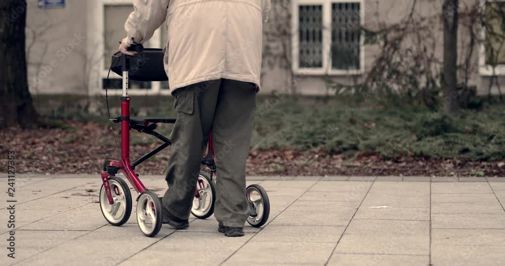 Old man walking on the city street with his red color walker. 4K Footage - Video