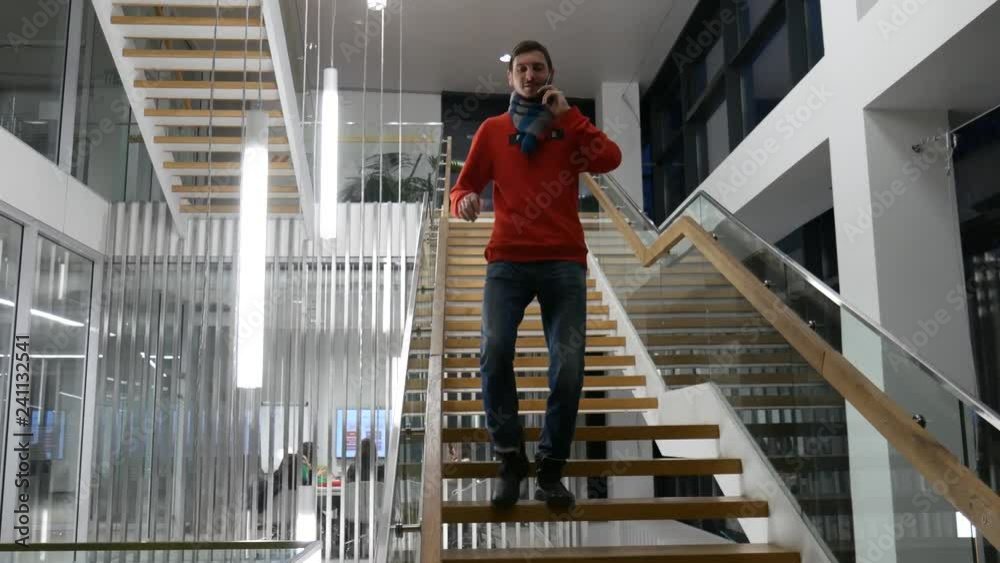 A handsome man sitting in the office on the stairs and talking on the phone. Freelancer in the workflow in an informal setting. 4k video A handsome man sitting in the office on the stairs and talking on the phone. Freelancer in the workflow in an informal setting. 4k video