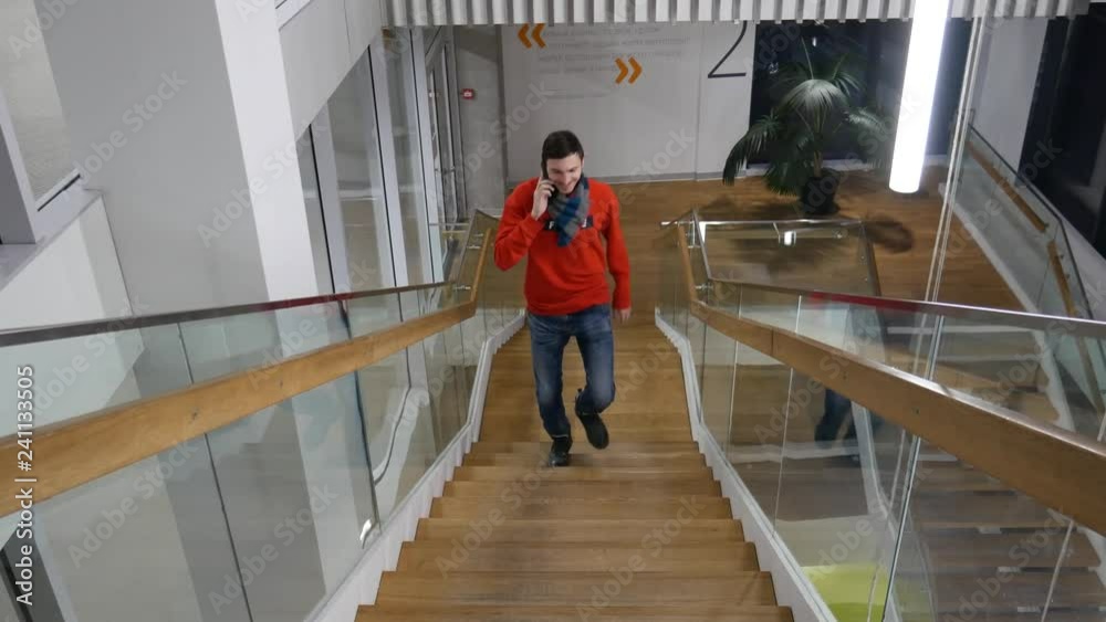 A handsome man sitting in the office on the stairs and talking on the phone. Freelancer in the workflow in an informal setting. 4k video A handsome man sitting in the office on the stairs and talking on the phone. Freelancer in the workflow in an informal setting. 4k video