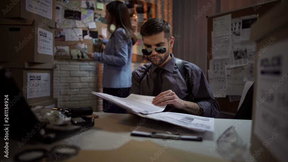 Private detective reading papers of criminal case, systematizing information