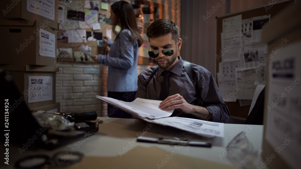 Private detective reading papers of criminal case, systematizing information Private detective reading papers of criminal case, systematizing information