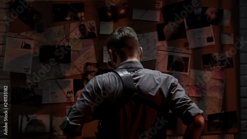 Detective looking at investigation board, searching for solution, back view © motortion