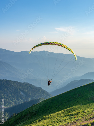 Yellow paraglider in blue clear sky over the Green Mountain