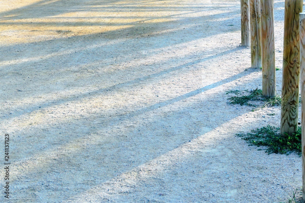 A fragment of a Spanish beach with coarse sand and wooden pillars as a background.