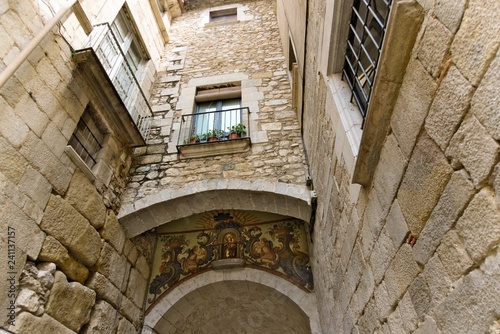 Interior view from the courtyard of a residential building in the old Girona on the house with a Catholic icon on the facade.