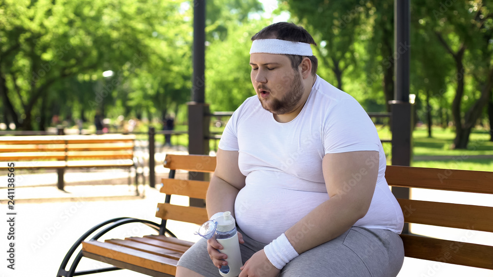Fat man breathing heavily and drinking amino acids after intense