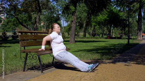 Obese girl exercising on bench in park, diligence, sport available in any place © motortion