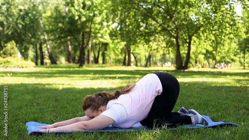 Fat woman stretching after exercising at park, active healthy lifestyle, nature