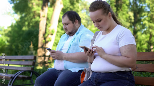 Photos Obese young couple chatting in social networks during date, shy and insecure
