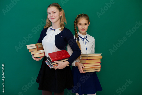 two girls schoolgirl is standing at the Blackboard with lesson books