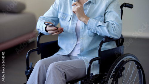 Senior lady in wheelchair chatting on smartphone, modern technologies, gadget
