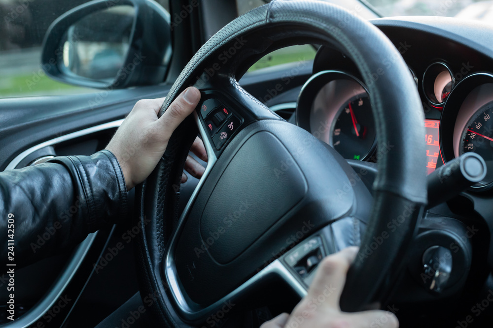 Male driver holding steering wheel while driving