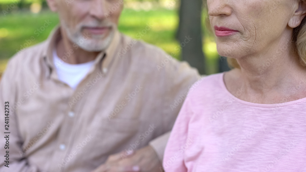 Handsome pensioner looking at pretty mature woman with interest sitting in park Handsome pensioner looking at pretty mature woman with interest sitting in park
