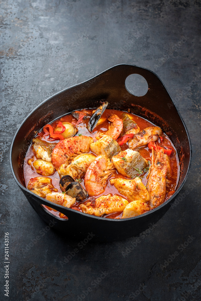 Traditional French Corsican fish stew with prawns, mussels and fish as top view in a modern design Japanese cast-iron roasting dish Traditional French Corsican fish stew with prawns, mussels and fish as top view in a modern design Japanese cast-iron roasting dish