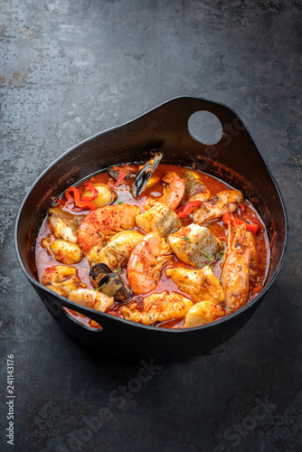 Traditional French Corsican fish stew with prawns, mussels and fish as top view in a modern design Japanese cast-iron roasting dish