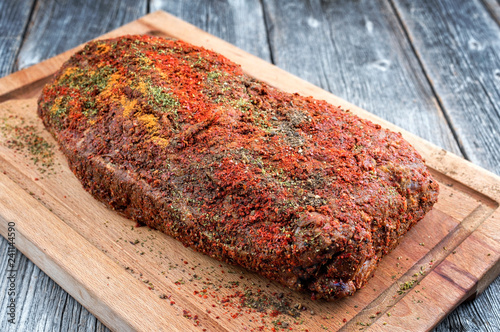 Traditional raw pulled pork piece of Bosten butt with spicy rub as closeup on a wooden cutting board photo
