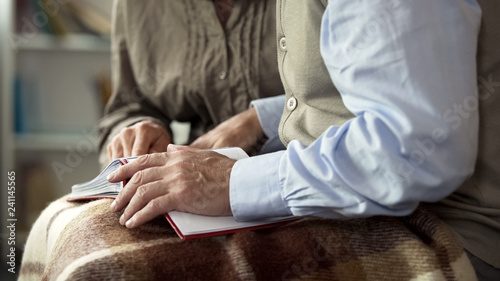Old couple viewing photos in album together, remembering happy moments nostalgia